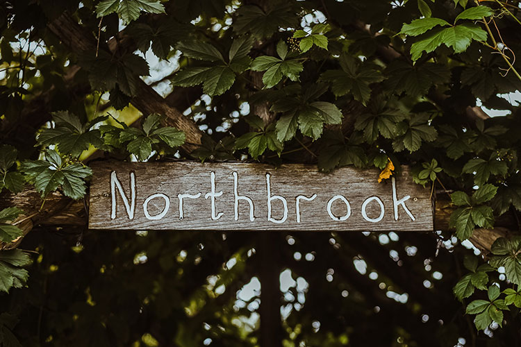 Northbrook Farm Wedding Venue - Sign saying Northbrook hung among green leaves